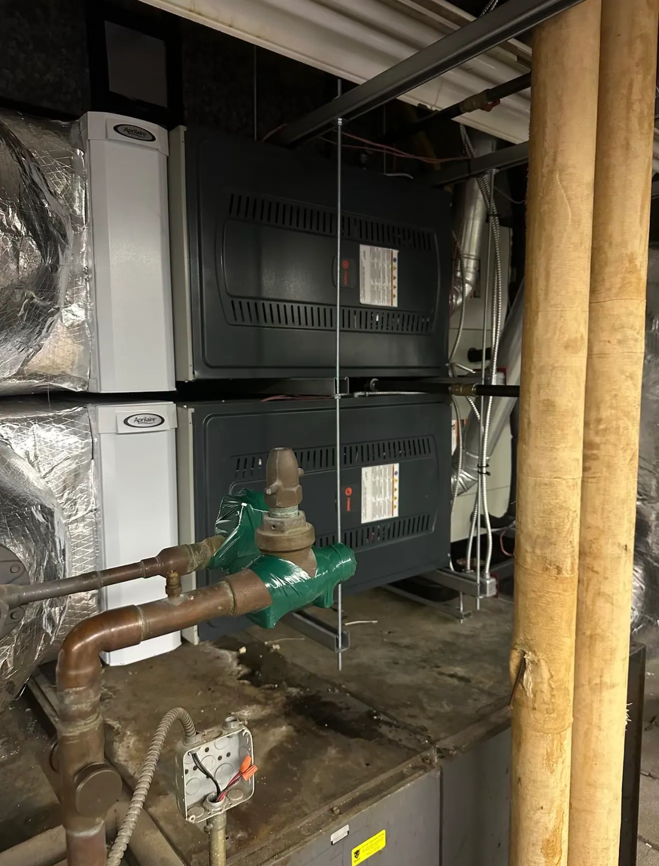 Two stacked Trane furnace cabinets with white AprilAire cabinets beside them, copper pipework and thick insulated pipes in the foreground.